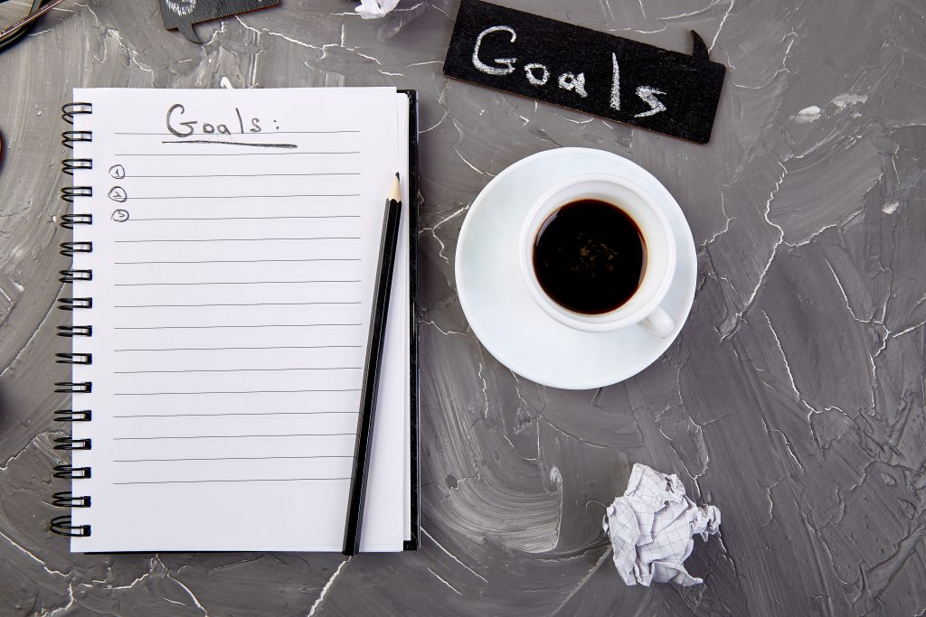 Goals as memo on notebook with idea, crumpled paper, cup of coffee